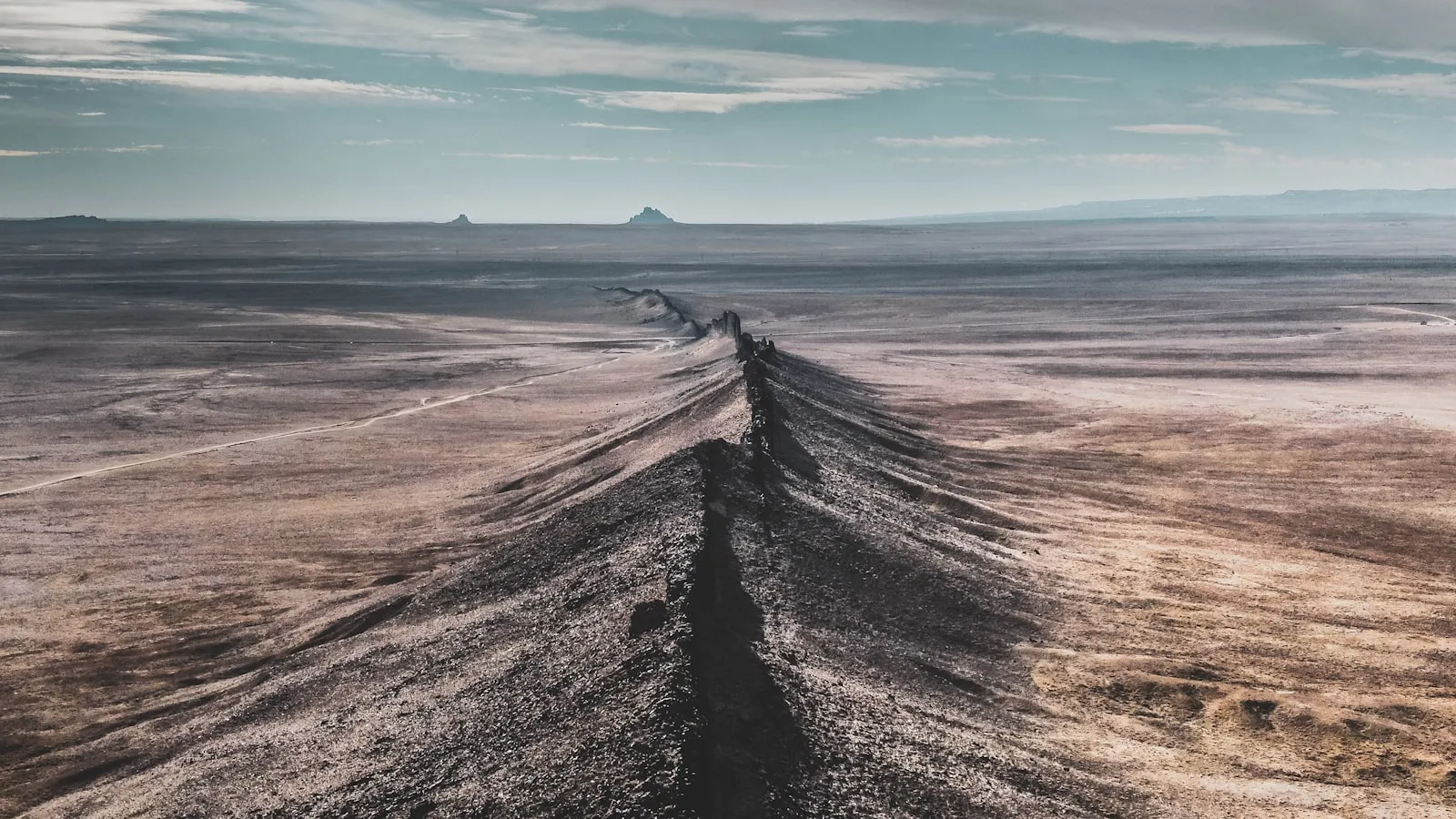 Aerial view of a vast, empty arid desert plain with only a faint dirt track — an undeveloped legacy subdivision lot.